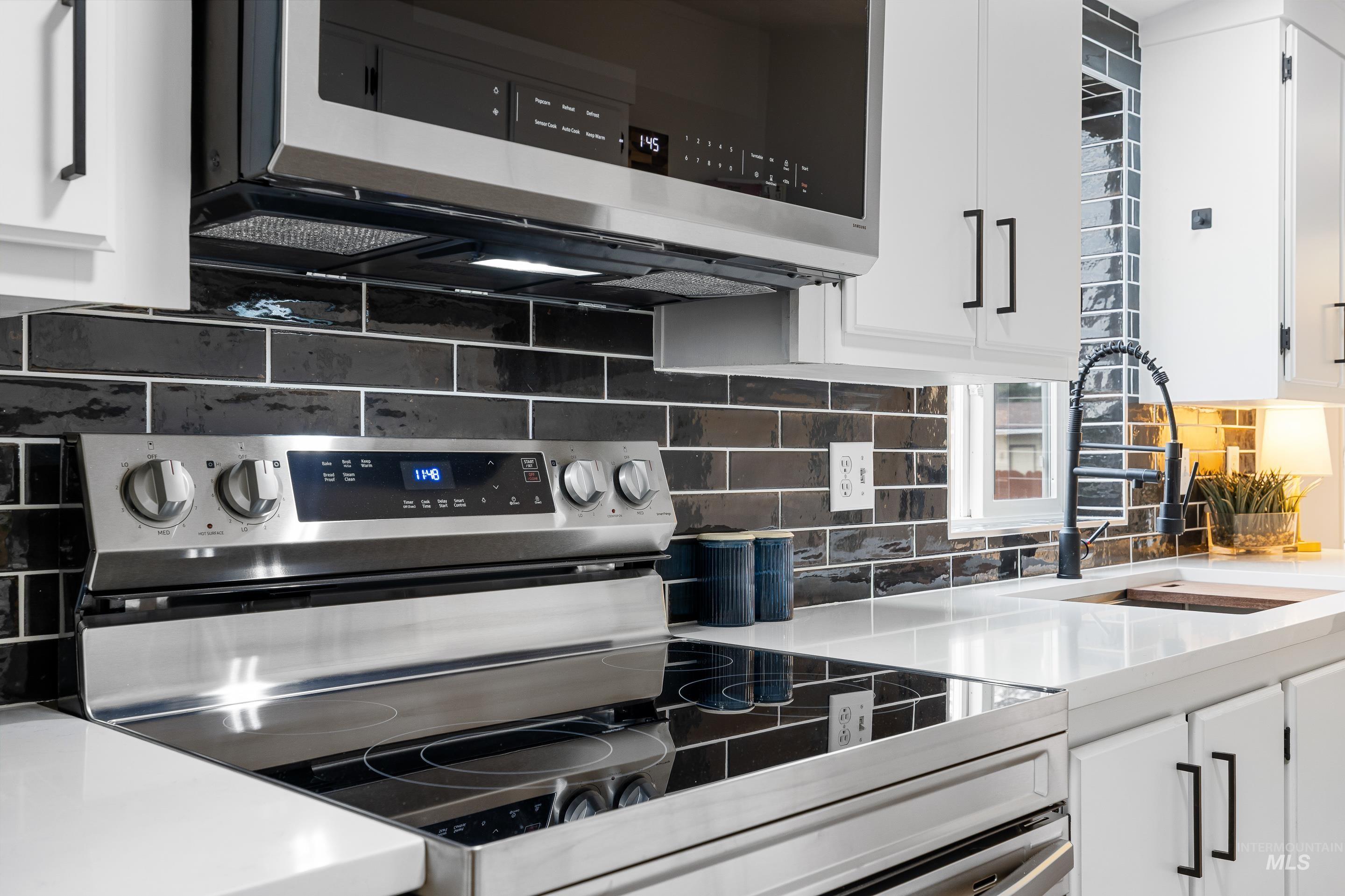 10014 Dewitt Lane Boise, ID 83704 - Photo 20 of 50 Kitchen featuring stainless steel appliances, tasteful backsplash, white cabinetry, and light stone countertops