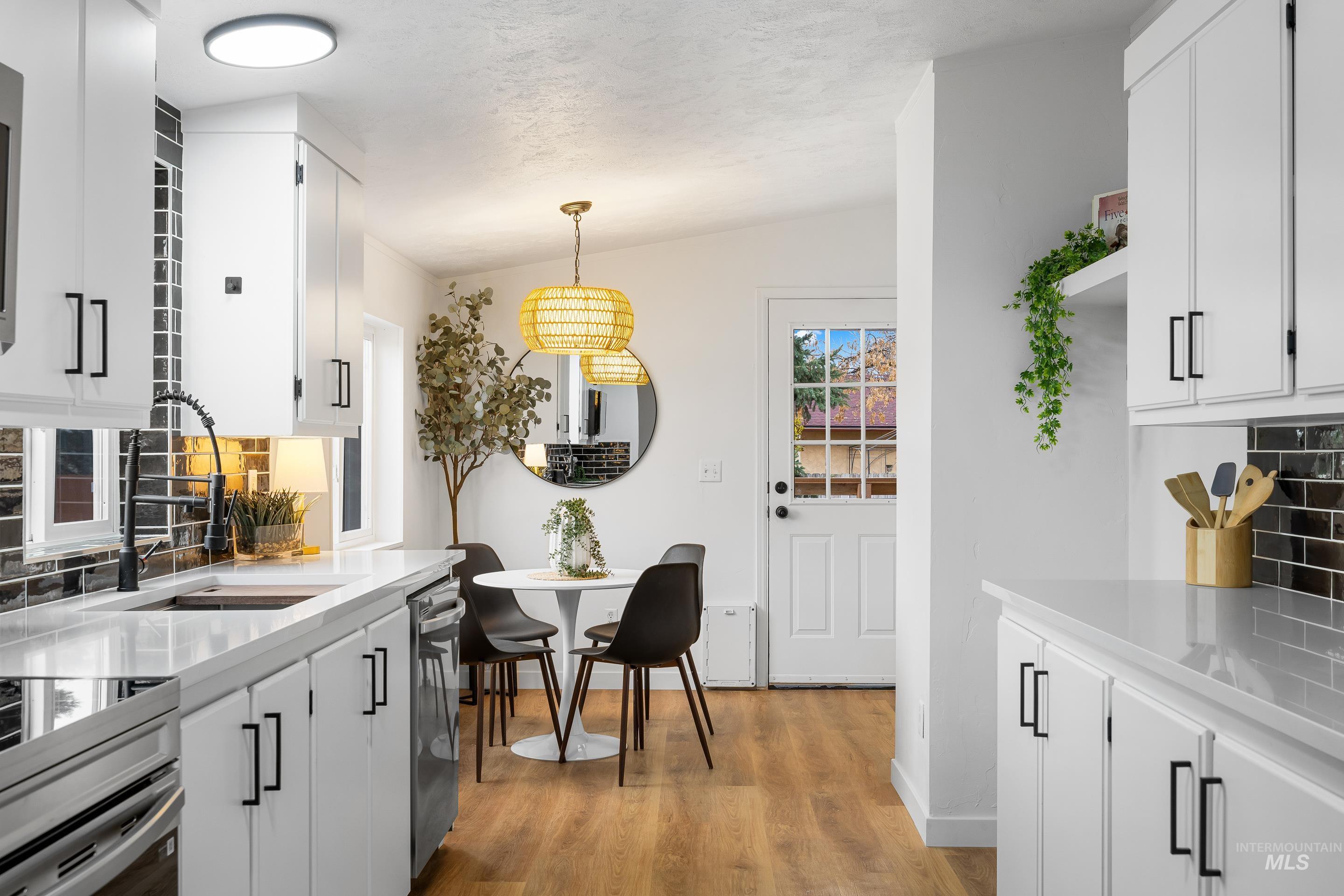 10014 Dewitt Lane Boise, ID 83704 - Photo 21 of 50 Kitchen featuring decorative backsplash, white cabinets, light wood-type flooring, hanging light fixtures, and vaulted ceiling