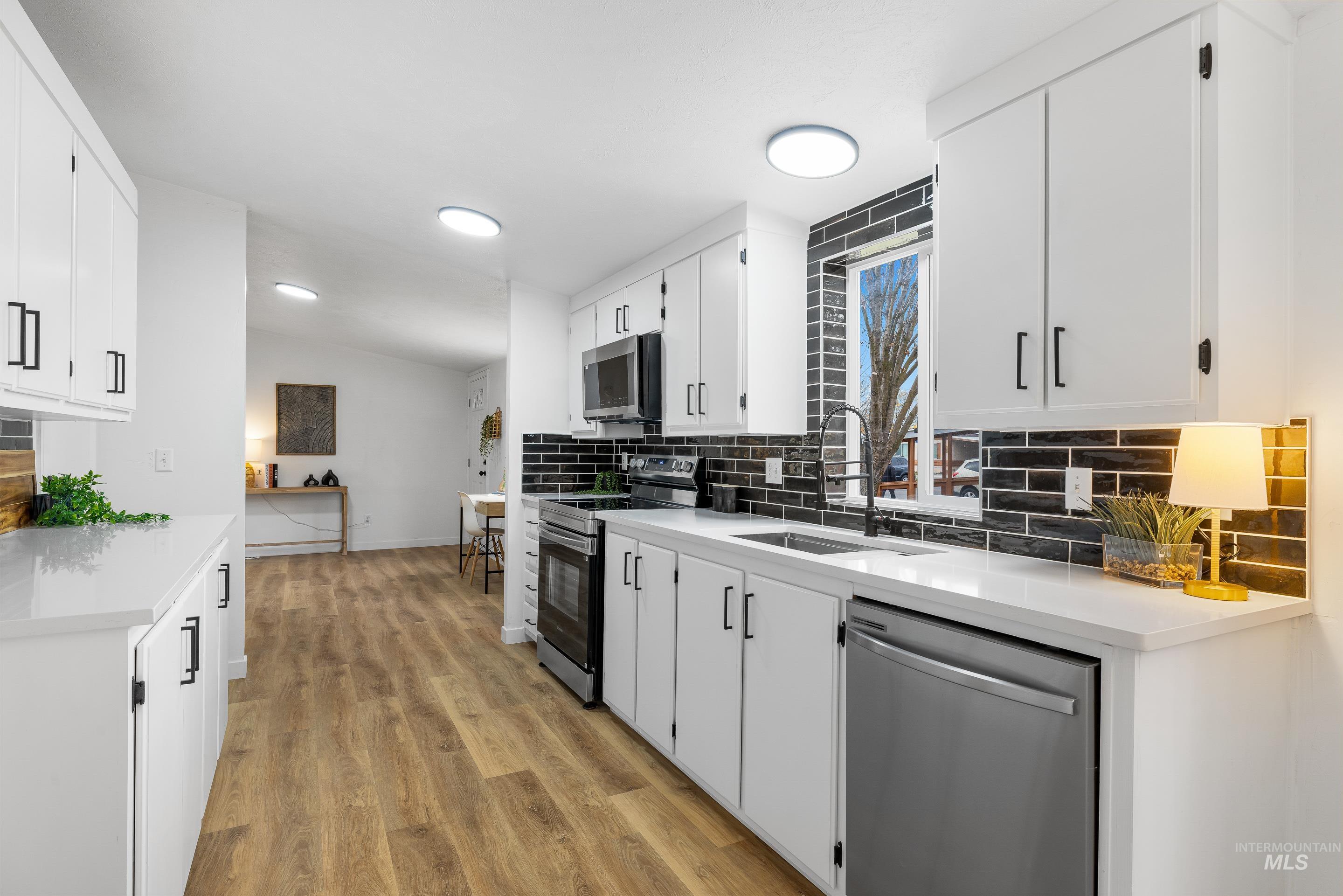 10014 Dewitt Lane Boise, ID 83704 - Photo 23 of 50 Kitchen with tasteful backsplash, stainless steel appliances, white cabinetry, light wood finished floors, and light stone countertops