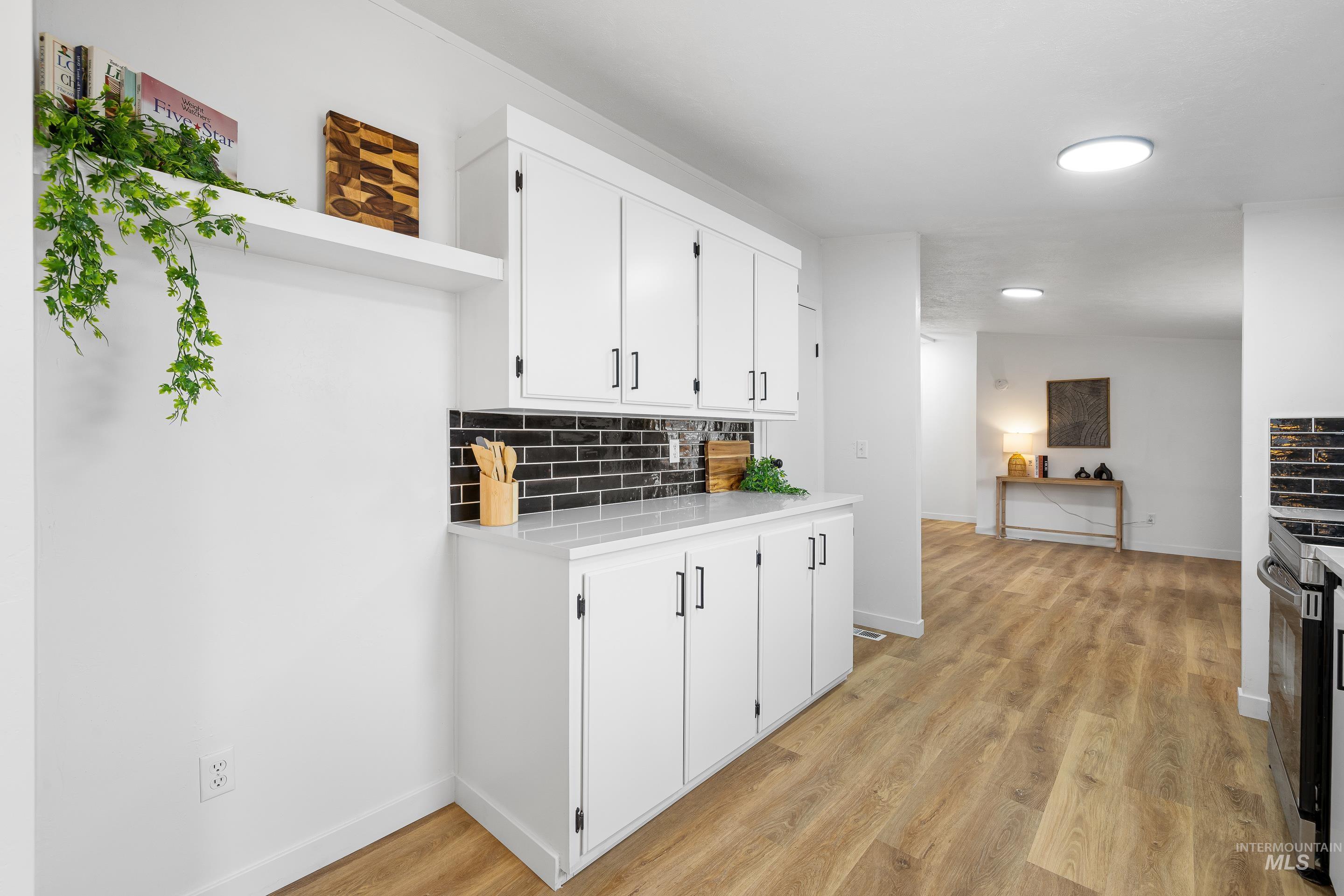 10014 Dewitt Lane Boise, ID 83704 - Photo 25 of 50 Kitchen with backsplash, light wood finished floors, white cabinets, open shelves, and stainless steel range with electric stovetop