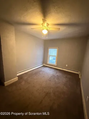 an empty room with a chandelier fan and windows