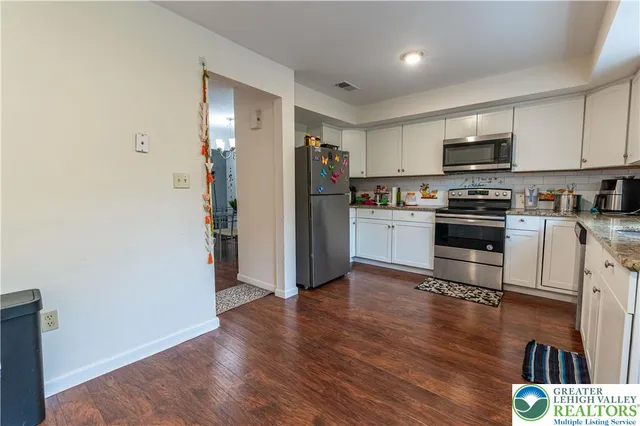 a kitchen with granite countertop a refrigerator and a stove top oven