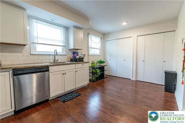 a kitchen with a sink window and wooden floor