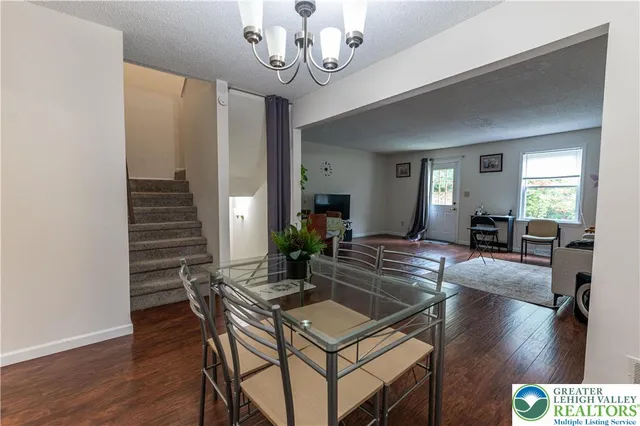 a dining room with wooden floor a chandelier a wooden table and chairs