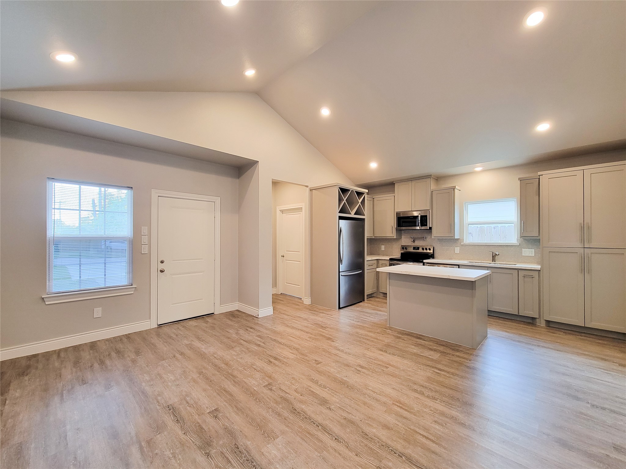 216 West Live Oak Street Angleton, TX 77515 - Photo 3 of 40 a large kitchen with stainless steel appliances granite countertop a large center island a stove a refrigerator with white cabinets and wooden floor