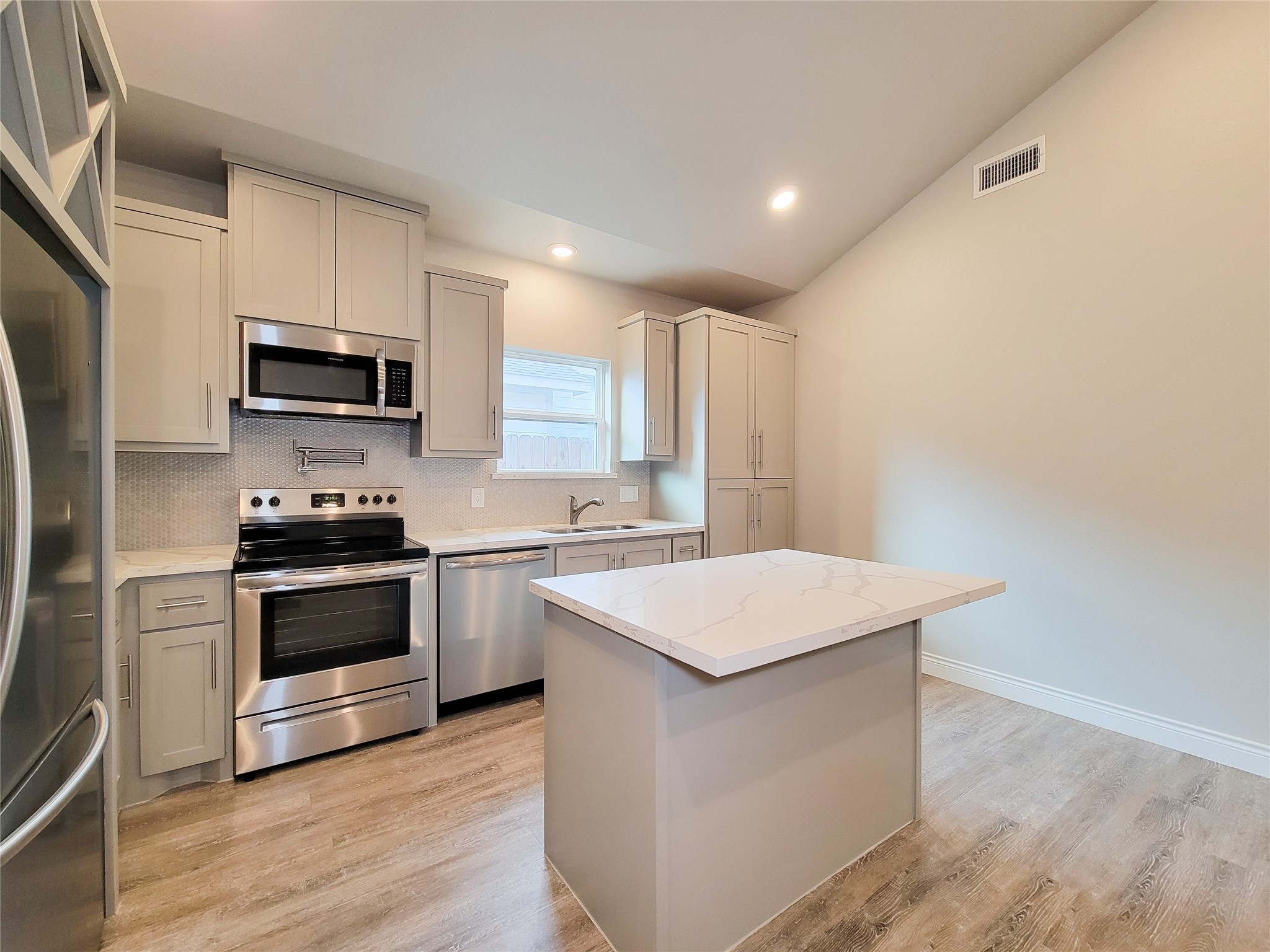 216 West Live Oak Street Angleton, TX 77515 - Photo 7 of 40 a kitchen with stainless steel appliances a stove a microwave and white cabinets