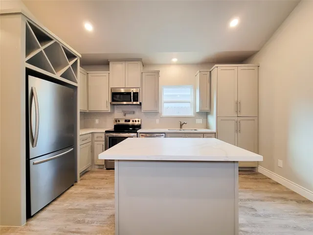 a kitchen with kitchen island a counter top space cabinets and stainless steel appliances