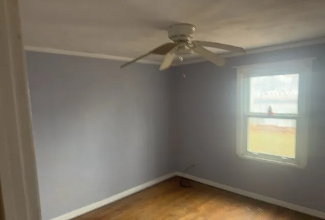 an empty room with a window and a fan