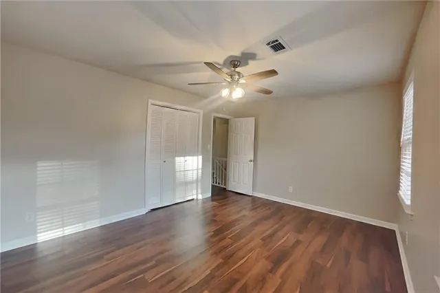 a view of an empty room with a window and wooden floor