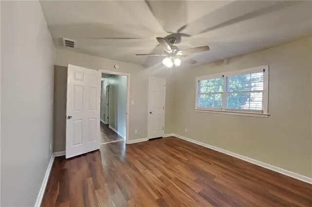 an empty room with wooden floor chandelier fan and windows
