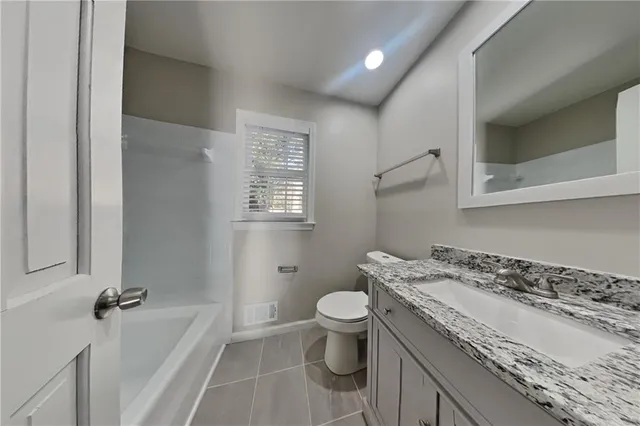 a bathroom with a granite countertop sink a toilet and a bathtub