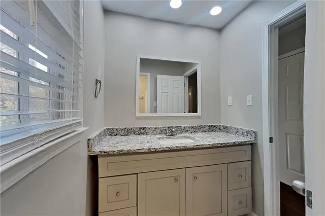 a bathroom with a granite countertop sink and a mirror