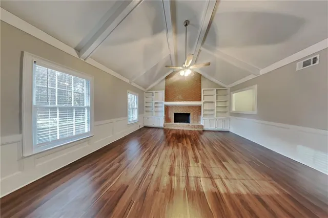 a view of empty room with wooden floor and fireplace