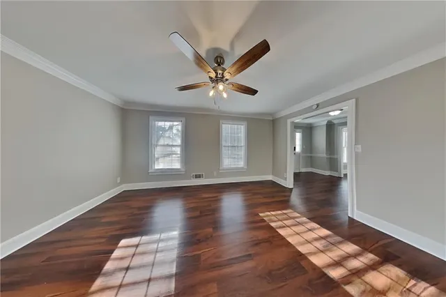 a view of an empty room with window and wooden floor