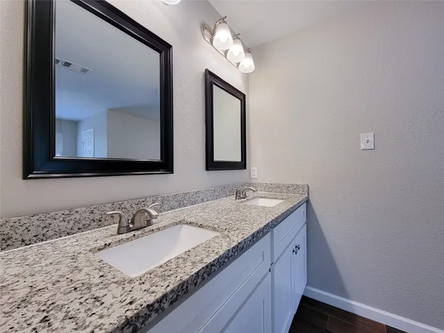 a bathroom with a granite countertop sink and a mirror