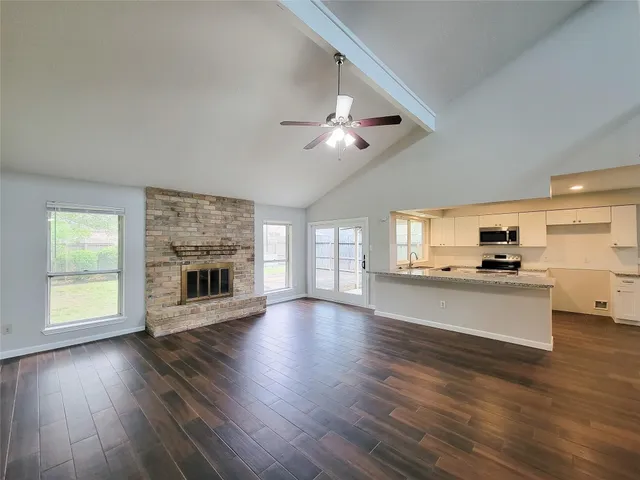 a living room with stainless steel appliances kitchen island hard wood floors and fireplace