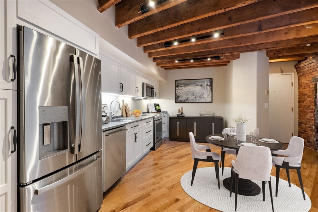 130 Fulton Street, Unit 16 Boston, MA 02109 - Photo 3 of 22 a kitchen with stainless steel appliances granite countertop a refrigerator a stove a sink a dining table and chairs with wooden floor