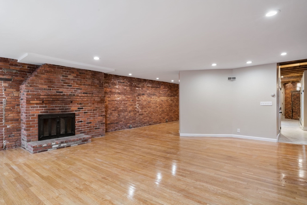 130 Fulton Street, Unit 16 Boston, MA 02109 - Photo 7 of 22 a view of empty room with wooden floor and fireplace