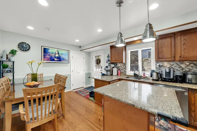 a kitchen with stainless steel appliances granite countertop a sink dishwasher a dining table and chairs with wooden floor