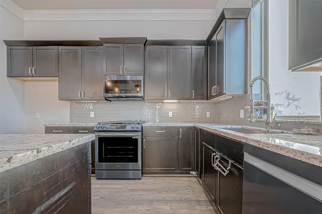 a kitchen with stainless steel appliances granite countertop a sink and a stove top oven
