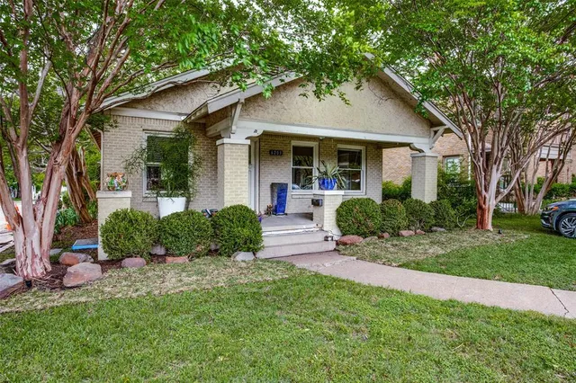 a front view of a house with a yard and potted plants