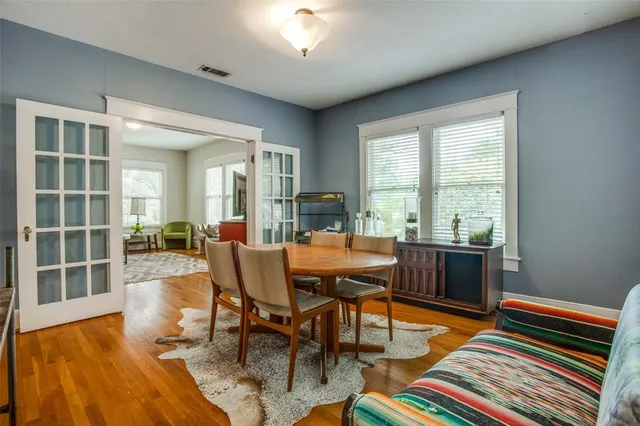 a dining room with wooden floor and windows