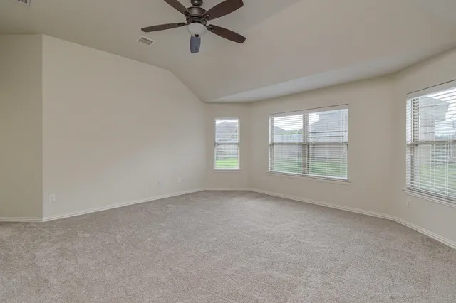 an empty room with wooden floor fan and windows
