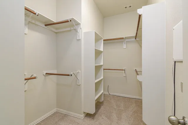 an empty room with a chandelier fan and windows