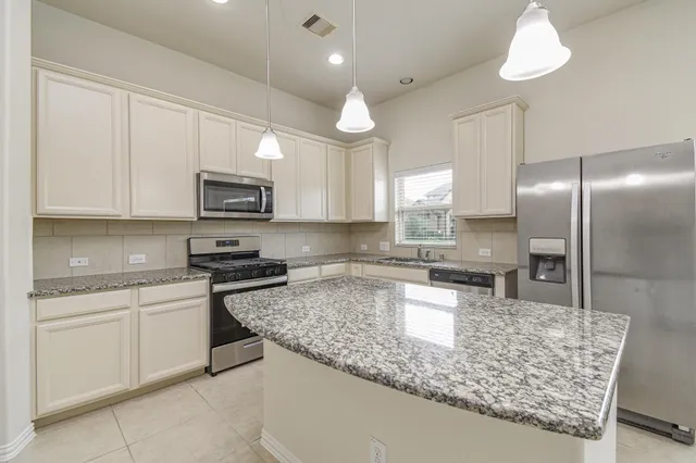 a kitchen with kitchen island granite countertop a sink a counter top space stainless steel appliances and cabinets