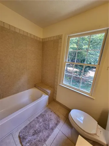 a bathroom with a sink a toilet a window and bathtub