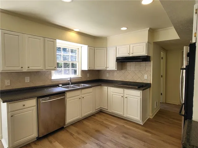 a kitchen with stainless steel appliances granite countertop a sink and cabinets with wooden floor