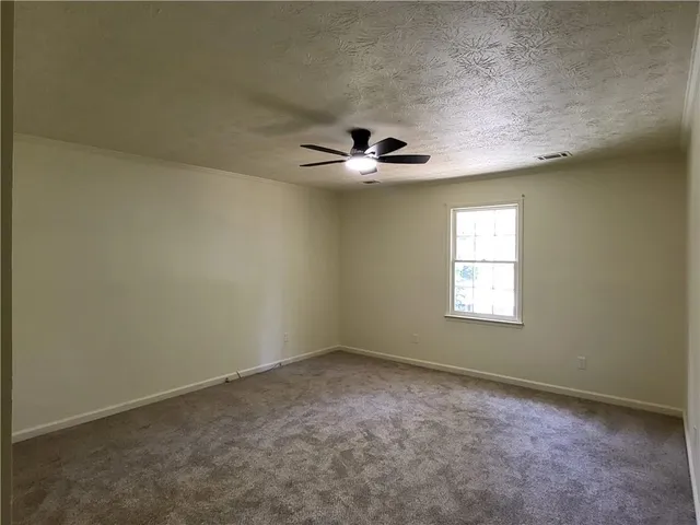 an empty room with windows and ceiling fan