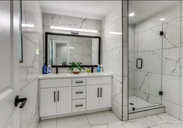 a bathroom with a double vanity sink a toilet a mirror and shower