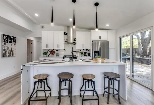 a kitchen with stainless steel appliances a dining table chairs refrigerator and wooden cabinets