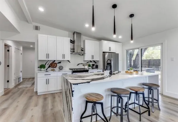 a kitchen with stainless steel appliances kitchen island granite countertop a dining table chairs and white cabinets