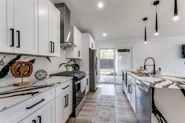 a kitchen with stainless steel appliances granite countertop a stove a sink and white cabinets