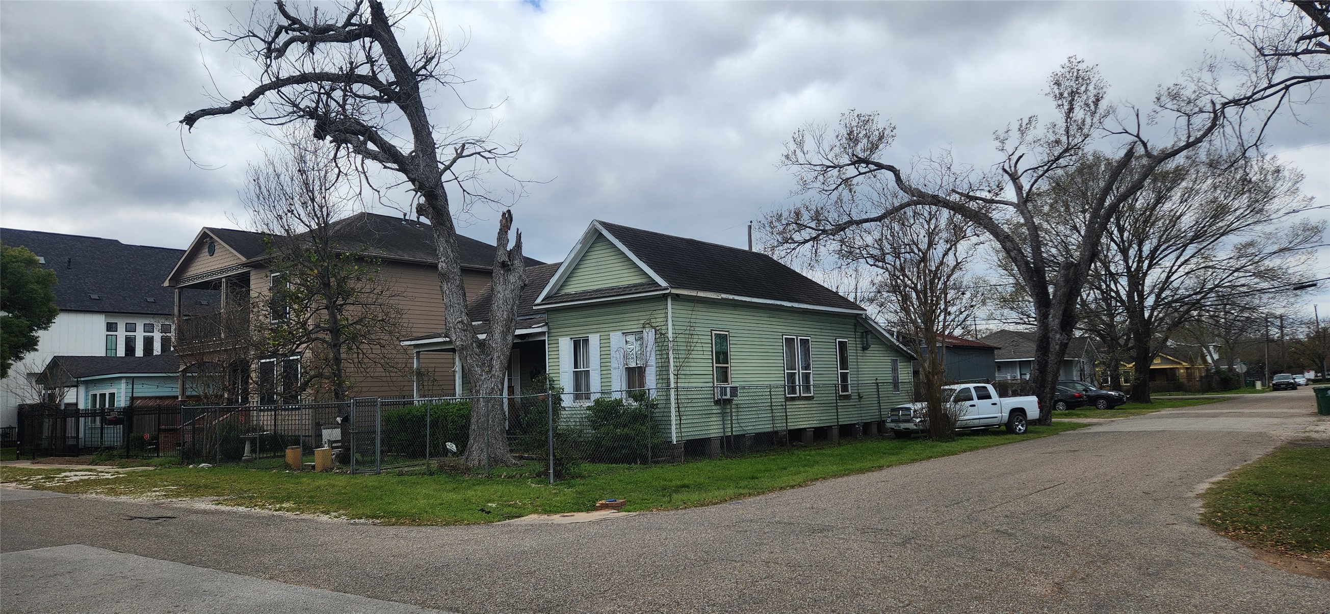 211 Tabor Street Houston, TX 77009 - Photo 2 of 11 a view of a white house next to a yard with big trees and plants