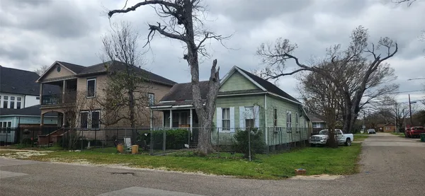a view of a white house next to a yard with big trees