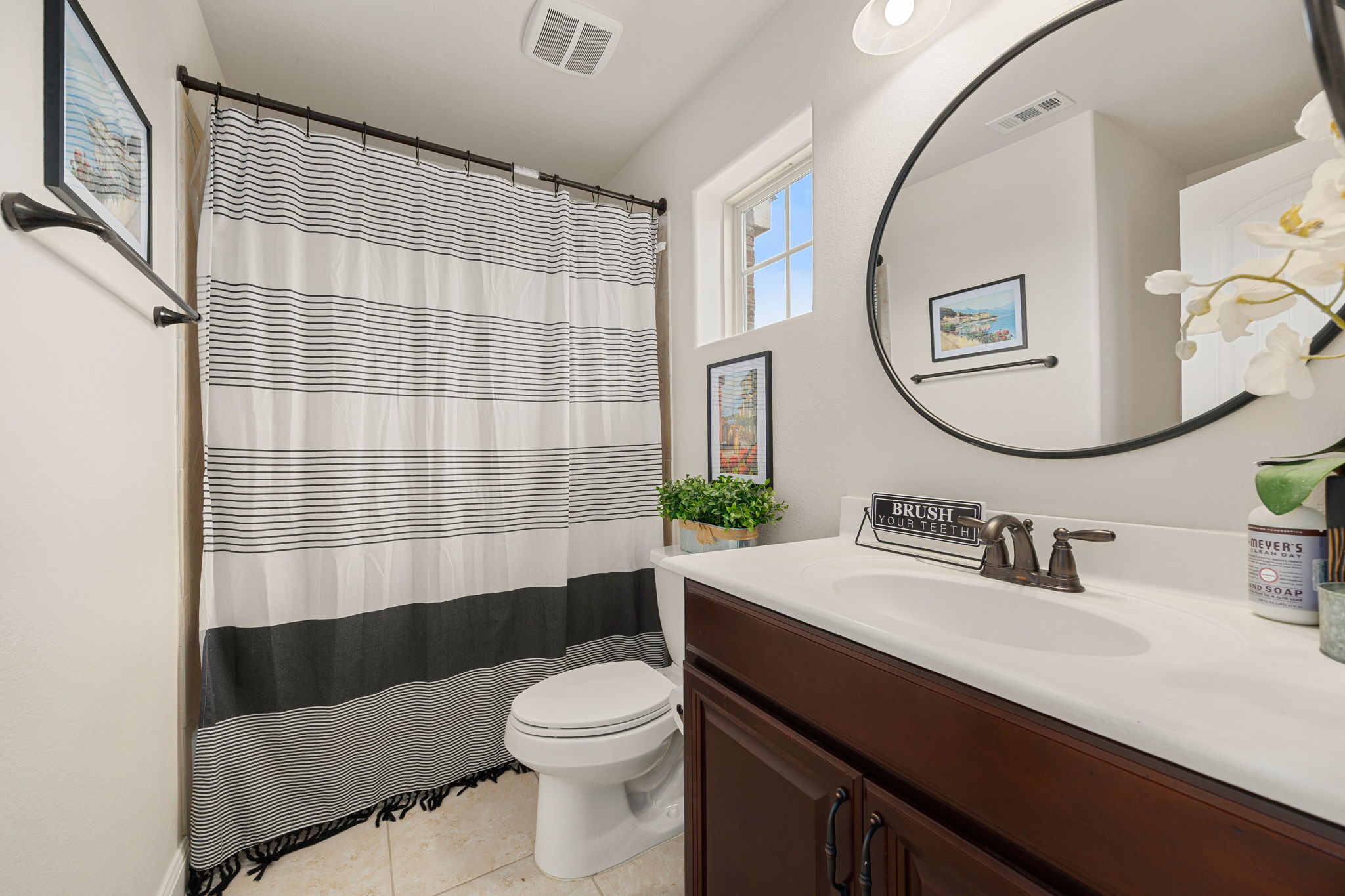 225 Pettigrew Path Buda, TX 78610 - Photo 28 of 38 a bathroom with a sink a toilet a mirror and shower curtain