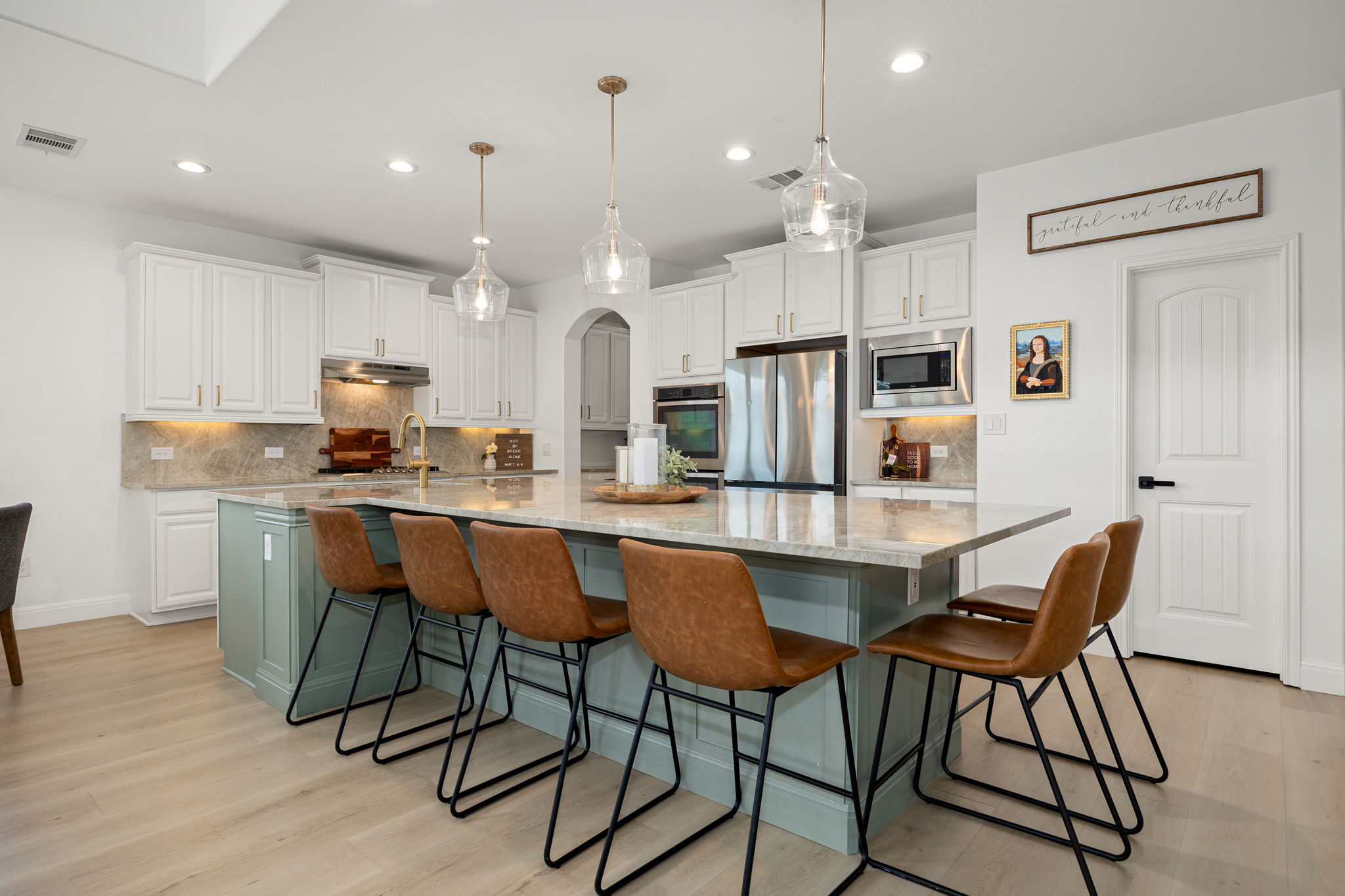 225 Pettigrew Path Buda, TX 78610 - Photo 9 of 38 a kitchen with a dining table chairs refrigerator and microwave