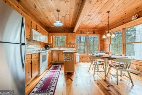 a kitchen with stainless steel appliances granite countertop a stove a refrigerator a dining table and chairs with the wooden floor