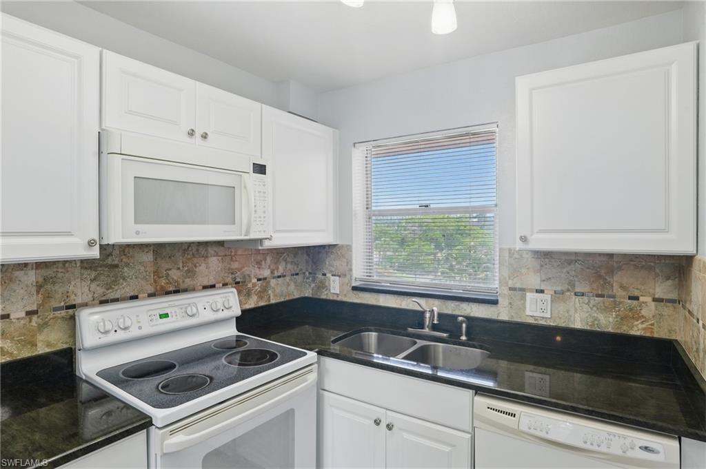 170 Turtle Lake Court, Unit 301 Naples, FL 34105 - Photo 6 of 23 a kitchen with granite countertop white cabinets sink and white appliances