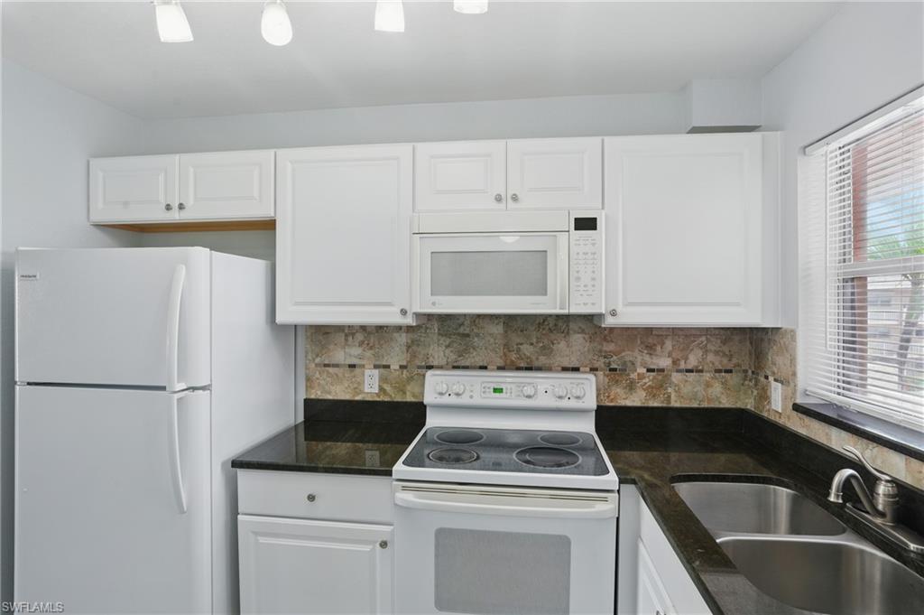 170 Turtle Lake Court, Unit 301 Naples, FL 34105 - Photo 7 of 23 a kitchen with white cabinets sink and white appliances