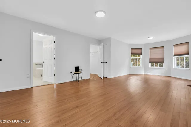 a view of an empty room with window and wooden floor