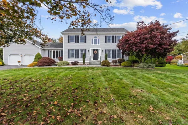 a front view of a house with garden and trees