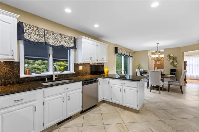 a large white kitchen with granite countertop lots of white cabinets