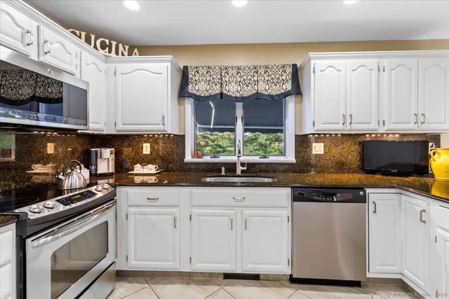 a kitchen with granite countertop a sink stainless steel appliances and cabinets