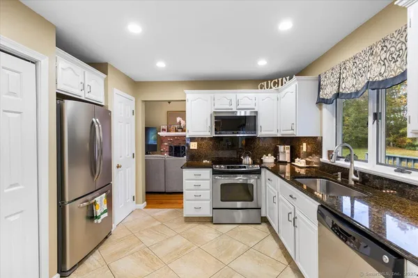 a large kitchen with stainless steel appliances granite countertop a stove a sink dishwasher a refrigerator and a microwave