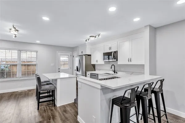 a kitchen with a table chairs a stove a microwave and cabinets