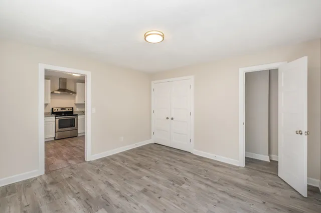 a view of kitchen and empty room with wooden floor